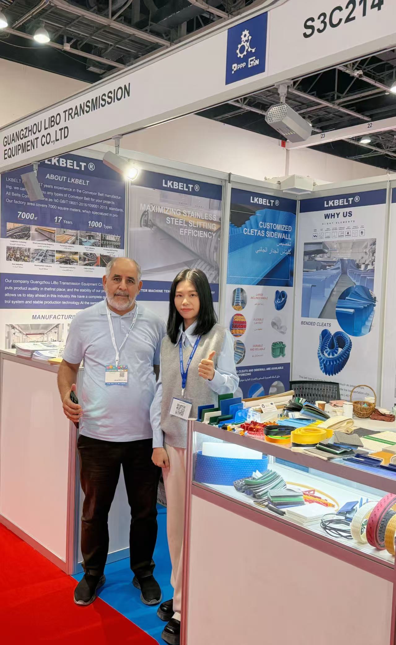 Visitors beside the LKBELT belt sample display at a Dubai trade show